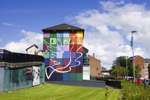 Bogside mural encouraging peace and tolerance, with a background of equally divided multicolor squares, and an oak leaf (the symbol of Derry) blended with a dove (a symbol for peace). This mural faces the Protestant walled city. 