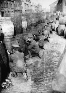 British troops using barrels to form a makeshift barricade from which they could safely fire at Volunteer held positions. 